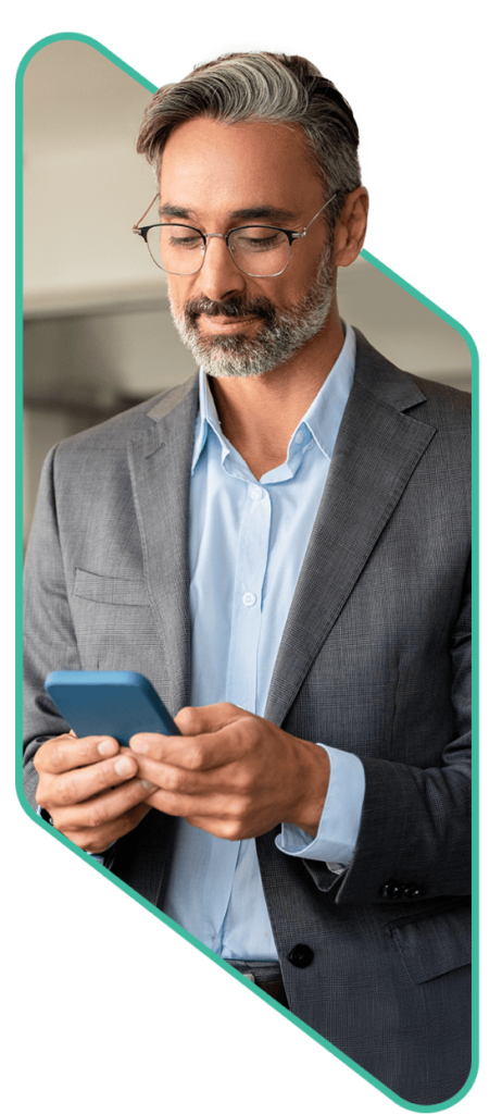 A middle-aged man with salt-and-pepper hair and a well-groomed beard is seen wearing a gray suit and a light blue dress shirt. He is holding a blue smartphone with both hands and appears focused while looking at the screen. He has a calm and confident expression. The image is framed within a modern, geometric border with a green outline, representing a professional engaging with Content Services solutions.